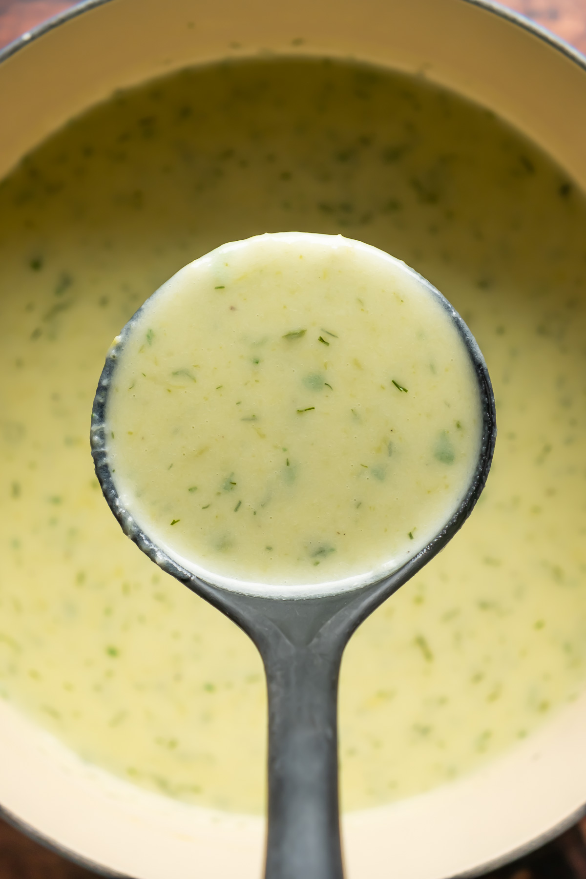 Vegan celery soup in a pot with a soup ladle.
